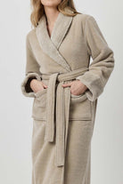 Woman wearing a beige robe against a white background