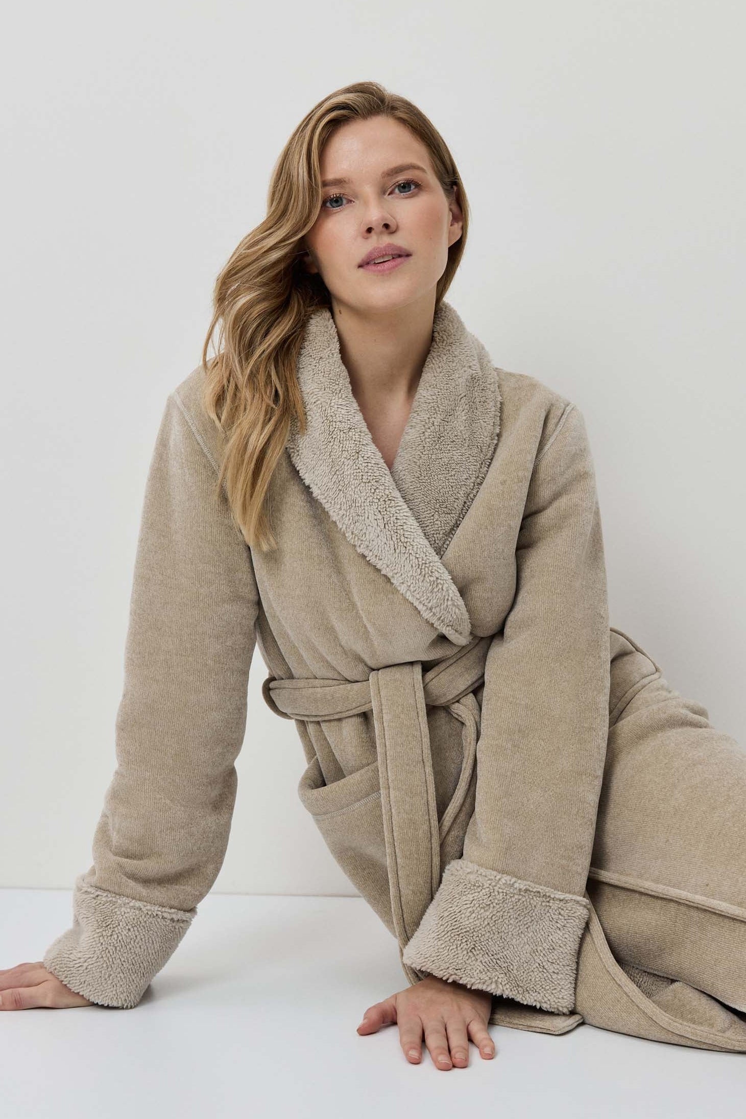 Woman wearing a beige robe against a white background