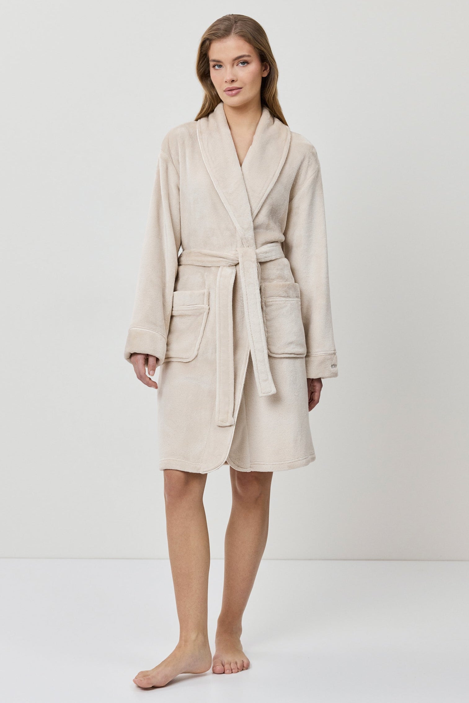 Woman wearing a beige bathrobe on a white background