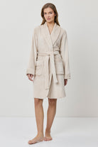 Woman wearing a beige bathrobe on a white background