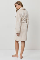 Woman wearing a beige bathrobe on a white background