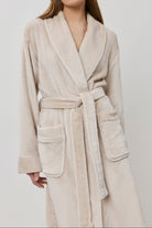 Woman wearing a beige bathrobe on a white background