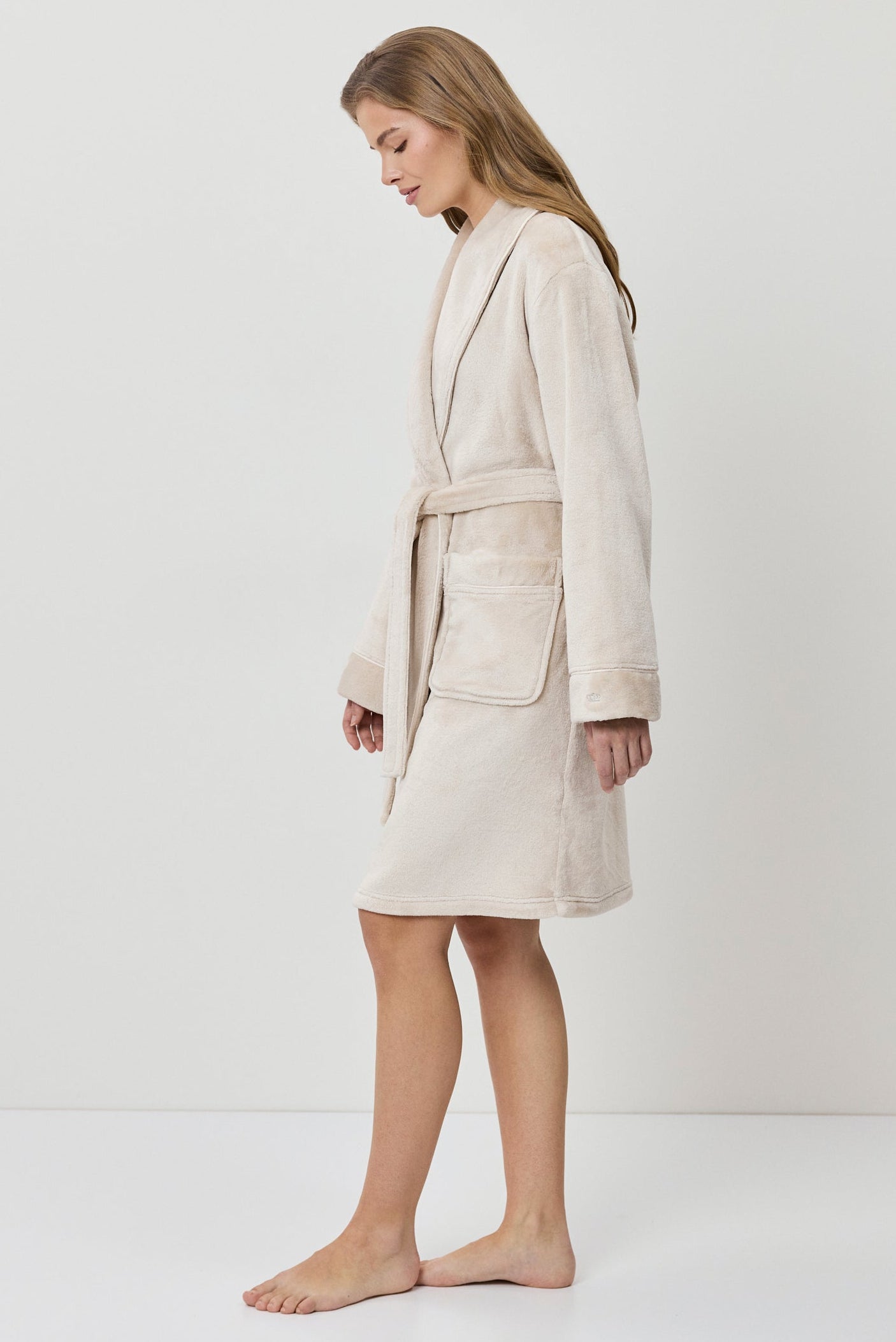 Woman wearing a beige bathrobe on a white background
