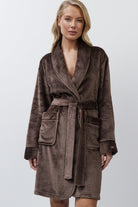 Woman wearing a brown bathrobe against a white background