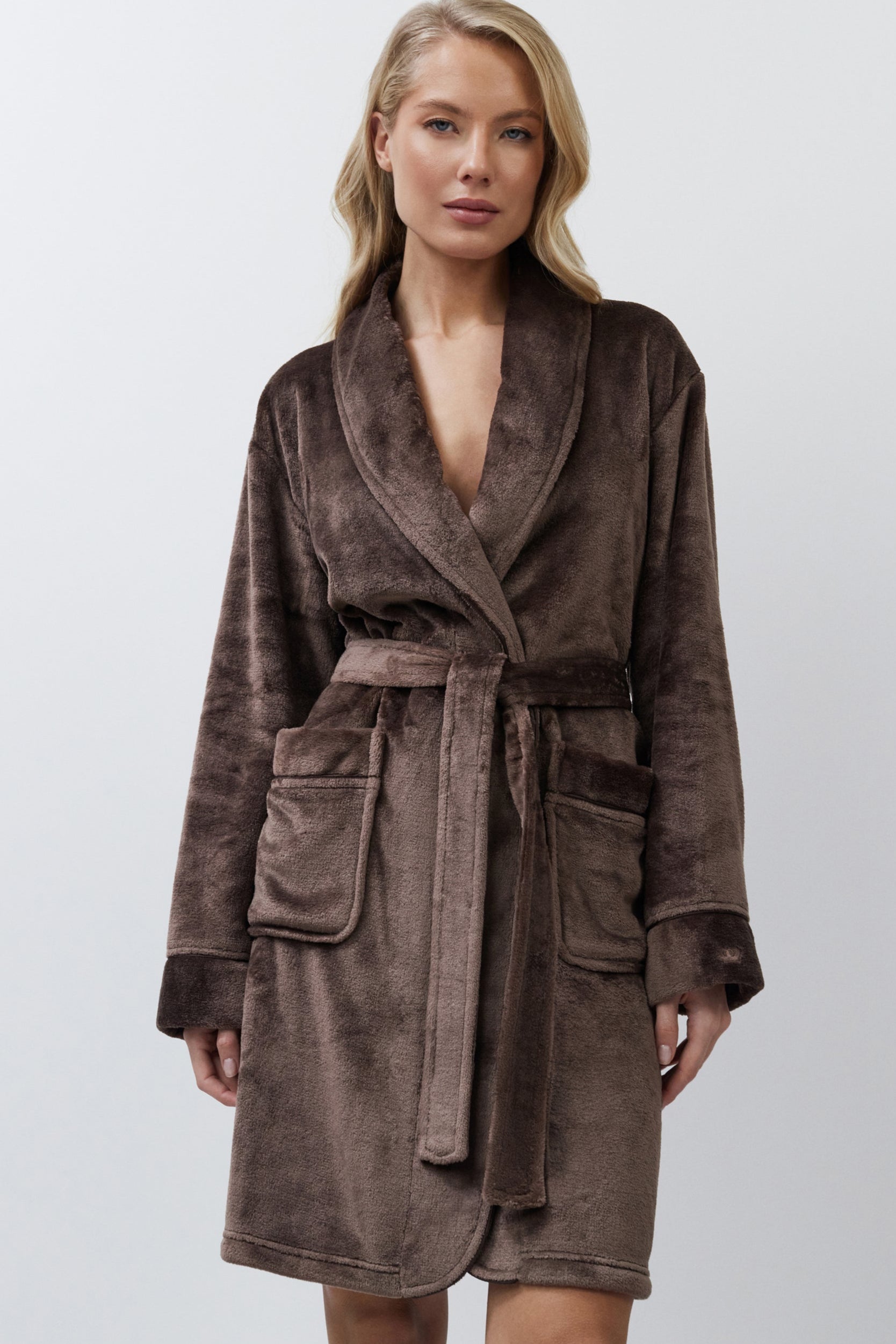 Woman wearing a brown bathrobe against a white background