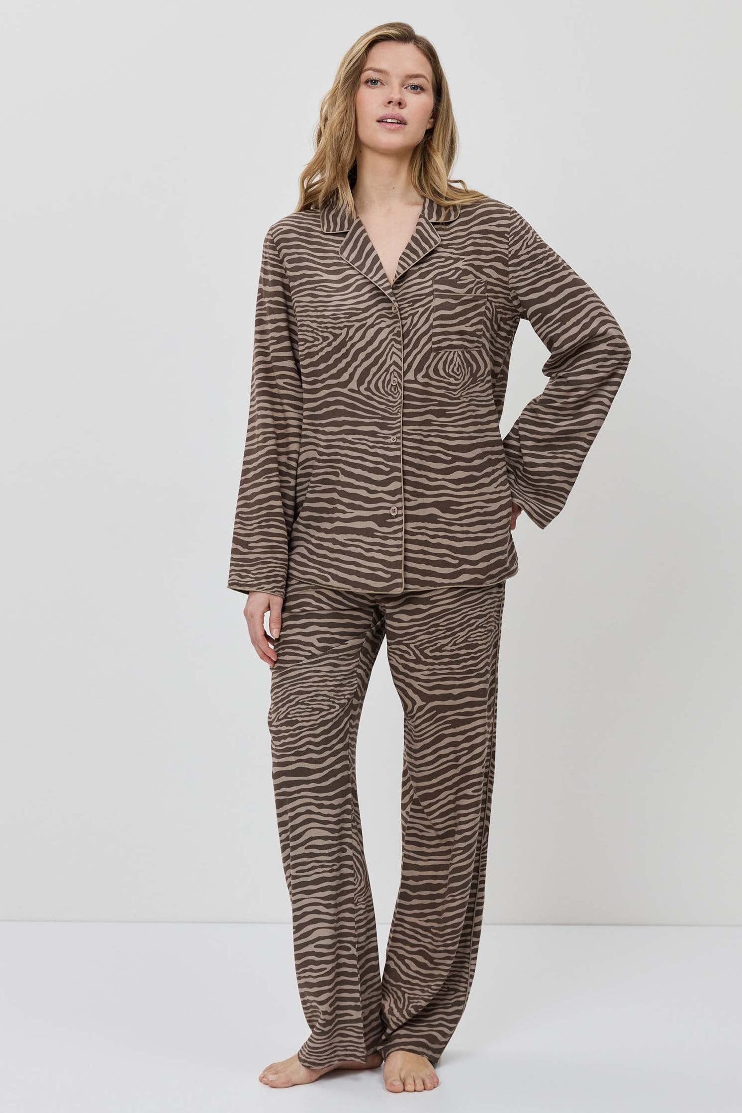 Woman wearing a brown and beige patterned pajama set on a white background.