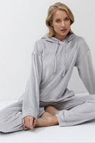 Woman wearing a gray hoodie and pants on a white background
