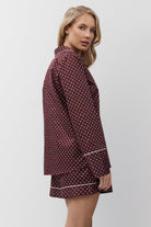 Woman wearing a burgundy pajama set on a white background