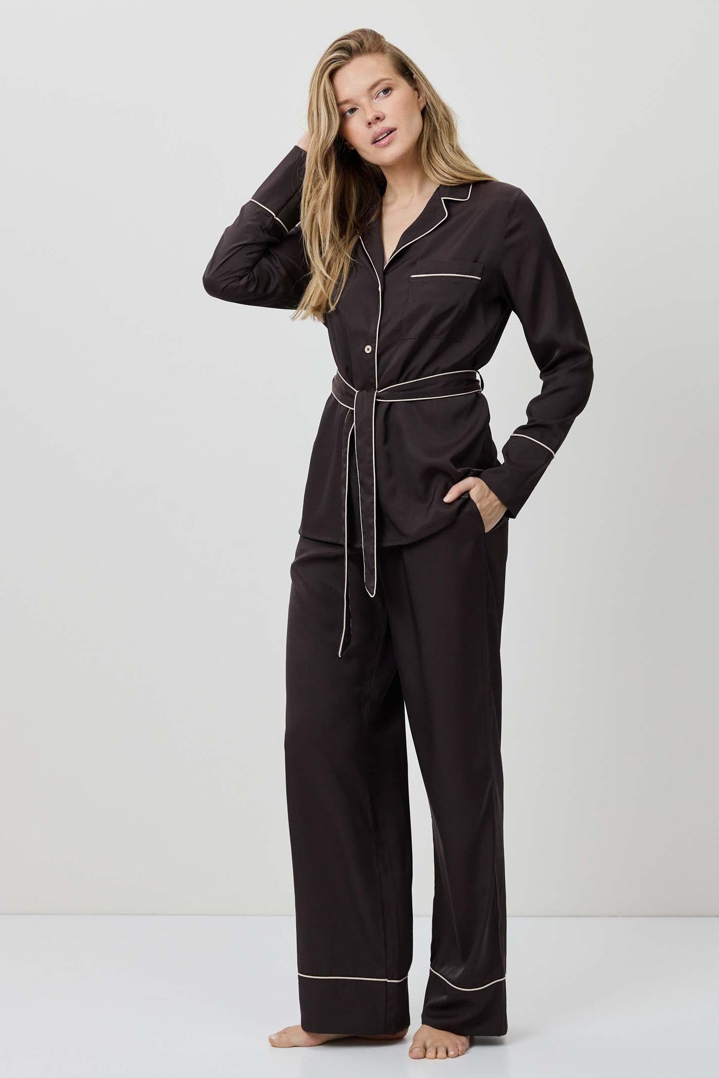 Woman wearing black pajamas with white piping on a white background