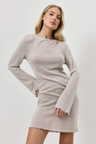 Woman wearing a light beige dress against a white background