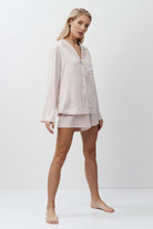 Woman wearing a light pink pajama set on a white background