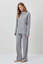 Woman wearing a gray pajama set against a white background