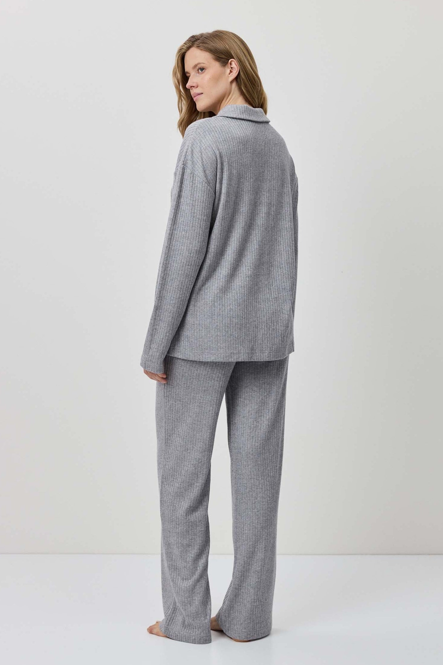 Woman wearing a gray suit standing against a white background