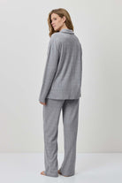 Woman wearing a gray suit standing against a white background