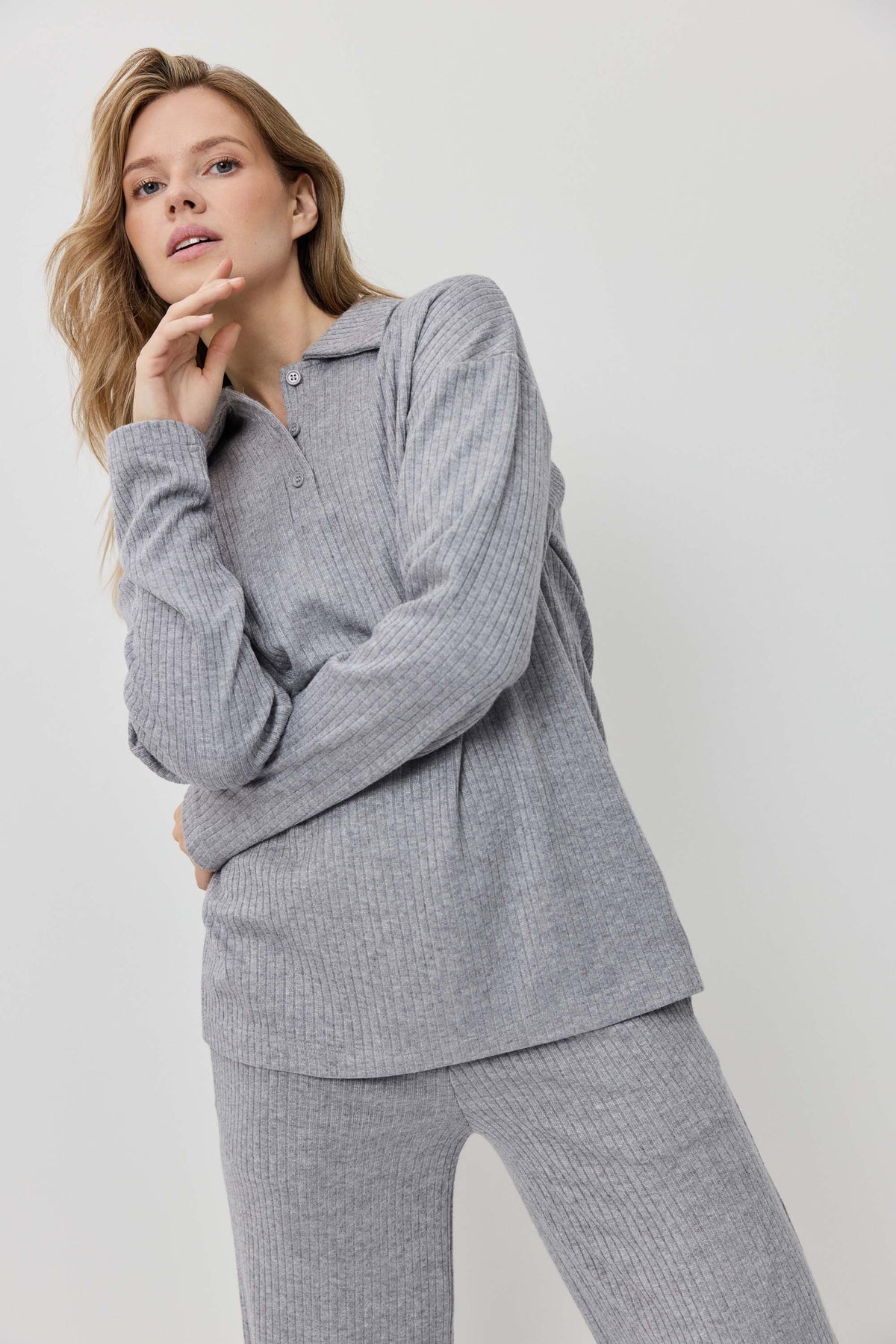 Woman wearing a gray ribbed loungewear set on a white background