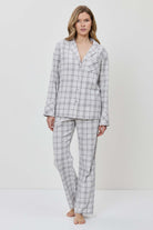 Woman wearing a gray checkered pajama set against a white background