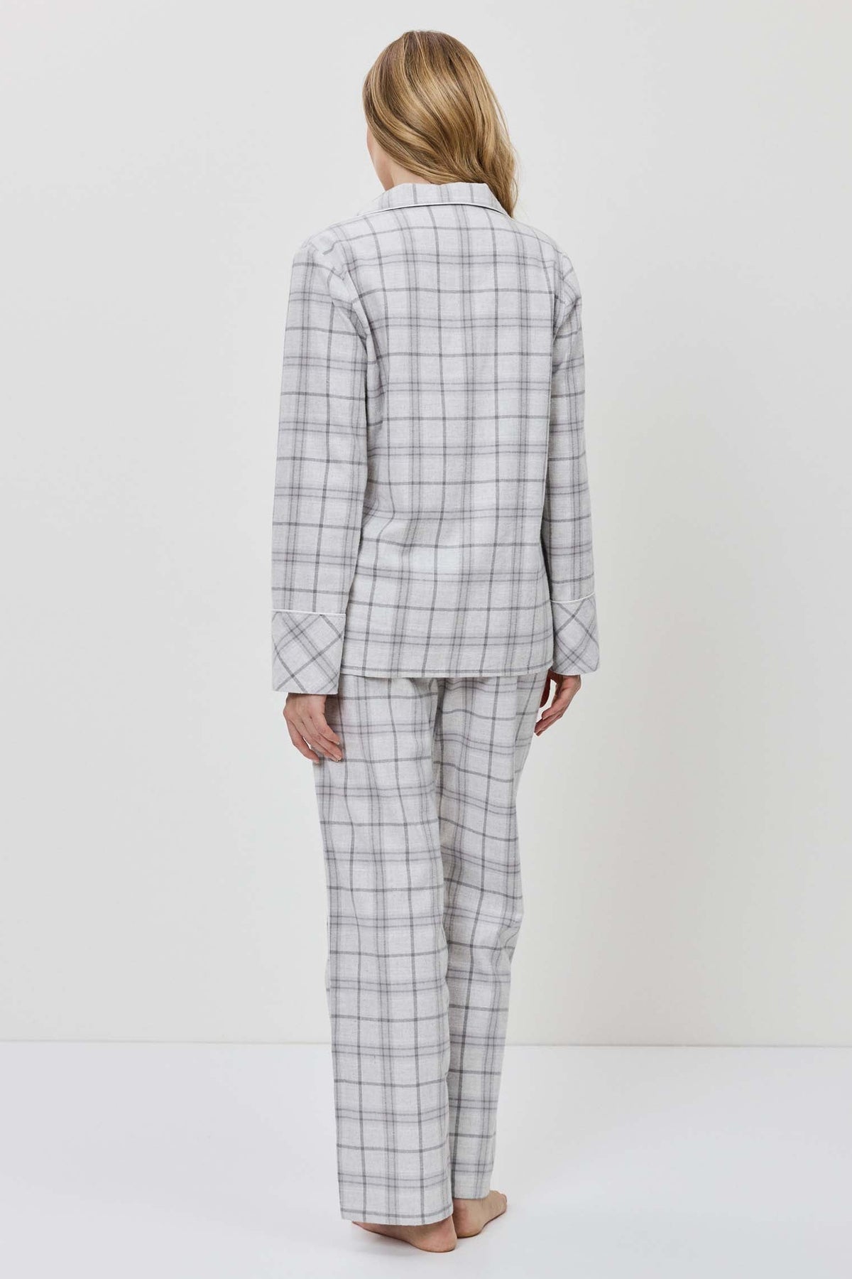 Person wearing a gray checkered suit standing against a white background