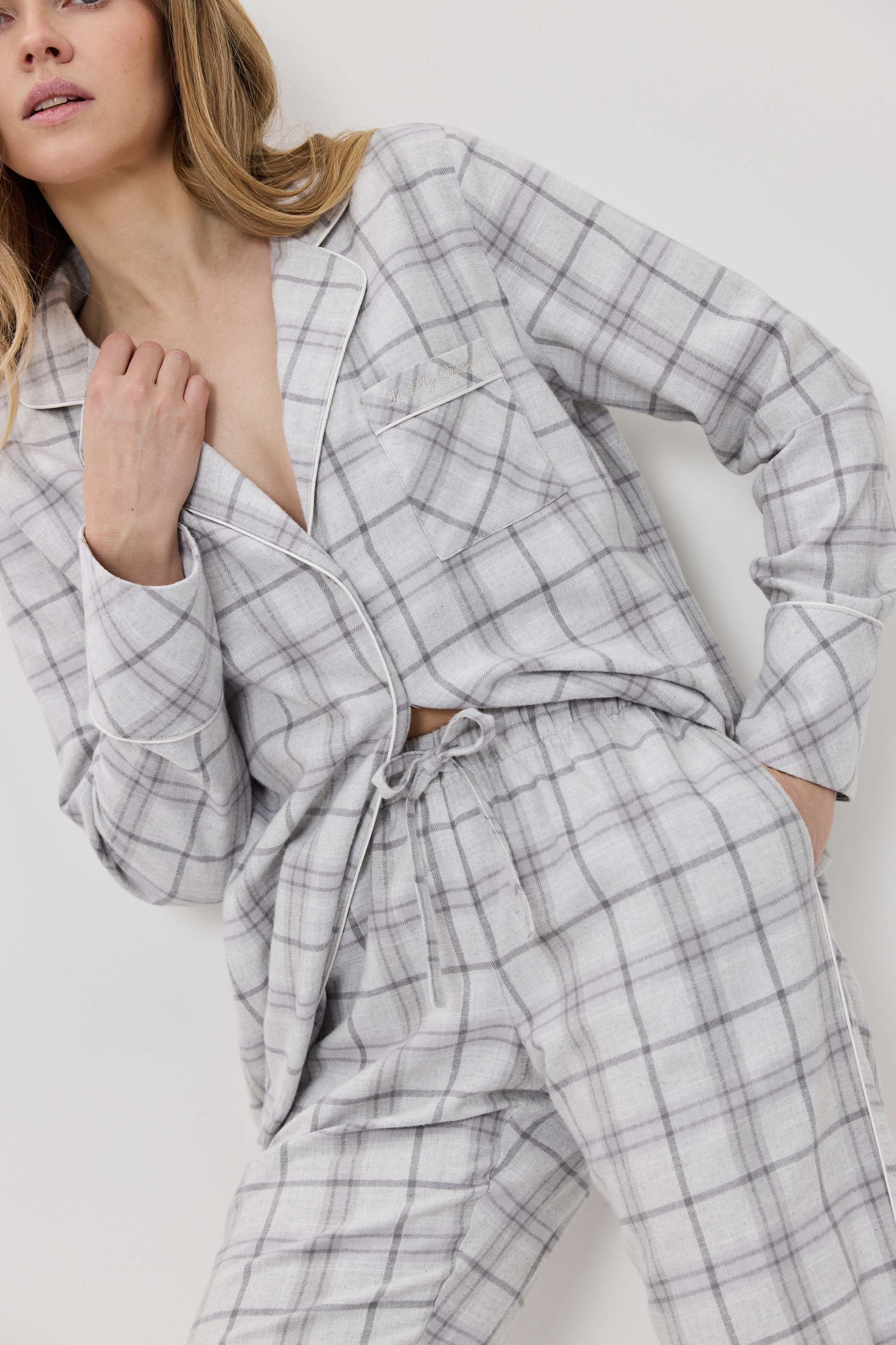 Woman wearing a gray plaid pajama set against a white background