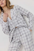 Woman wearing a gray plaid pajama set against a white background