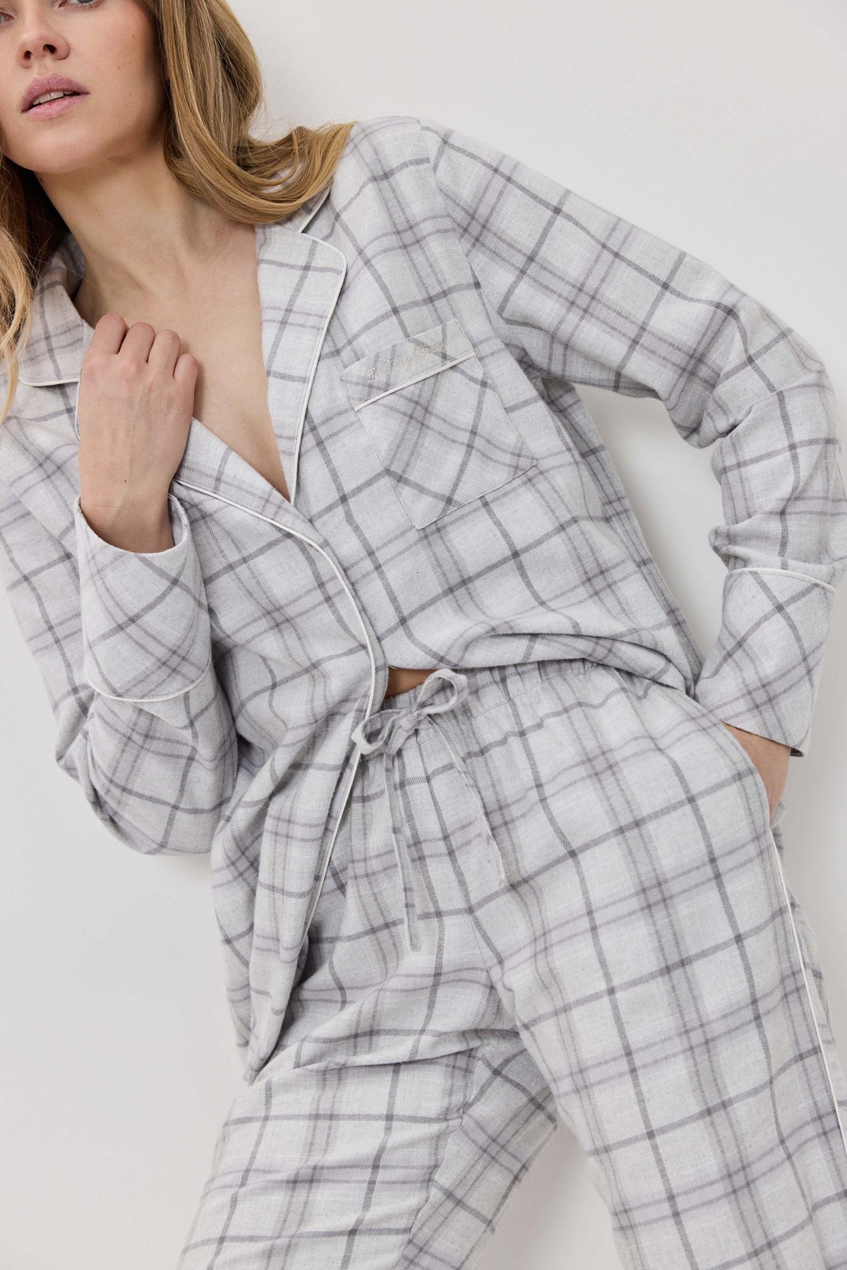 Woman wearing a gray plaid pajama set against a white background