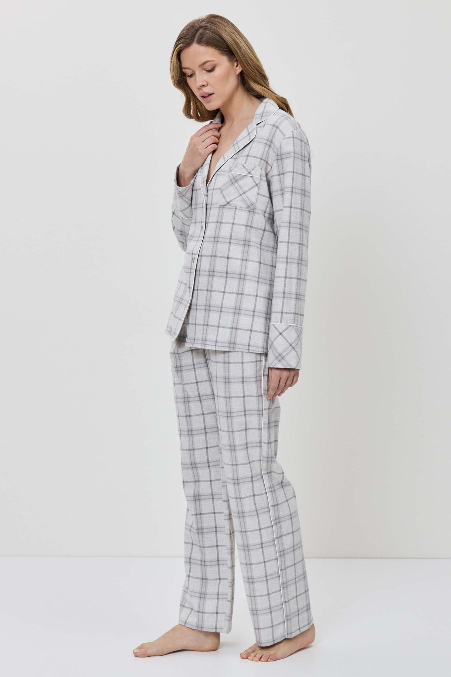 Woman wearing a gray checkered pajama set against a white background