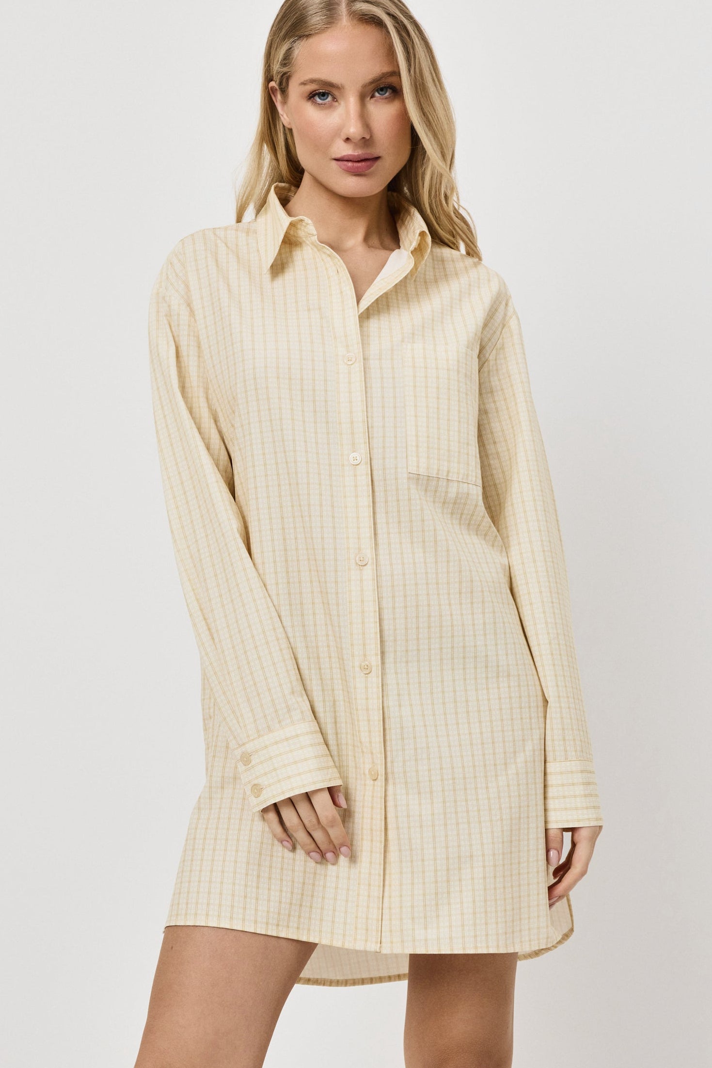 Woman wearing a light yellow ribbed shirt dress on a white background