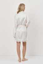 Person wearing a white gown against a plain background