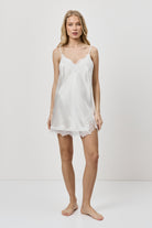 Woman wearing a white nightdress against a plain background