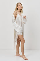 Woman wearing a white satin robe against a plain background