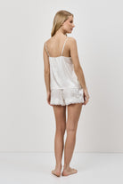 Woman wearing a white lace pajama set against a plain background