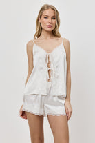 Woman wearing a white lace top and shorts on a plain background