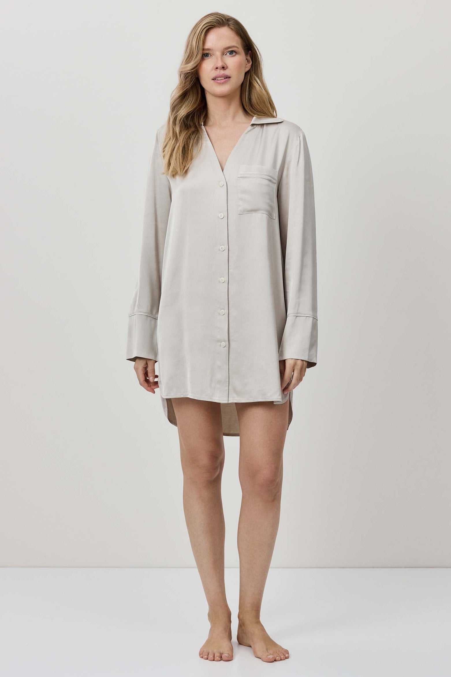 Woman wearing a beige shirt dress against a white background
