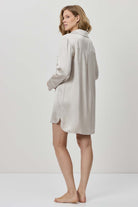 Woman wearing a light gray dress against a white background