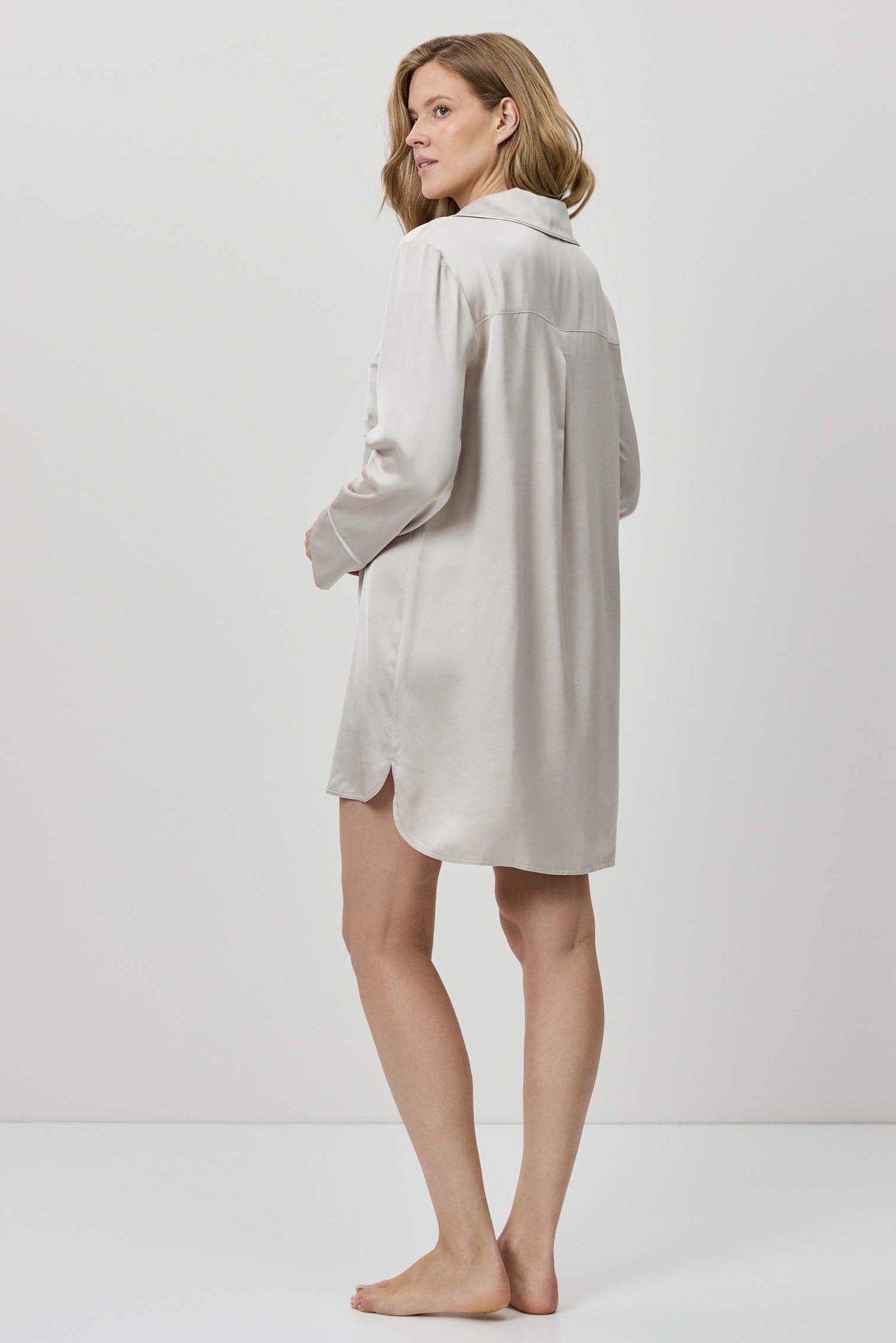 Woman wearing a light gray dress against a white background