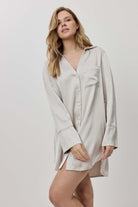 Woman wearing a beige shirt dress against a white background