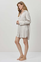 Woman wearing a light-colored nightshirt against a white background