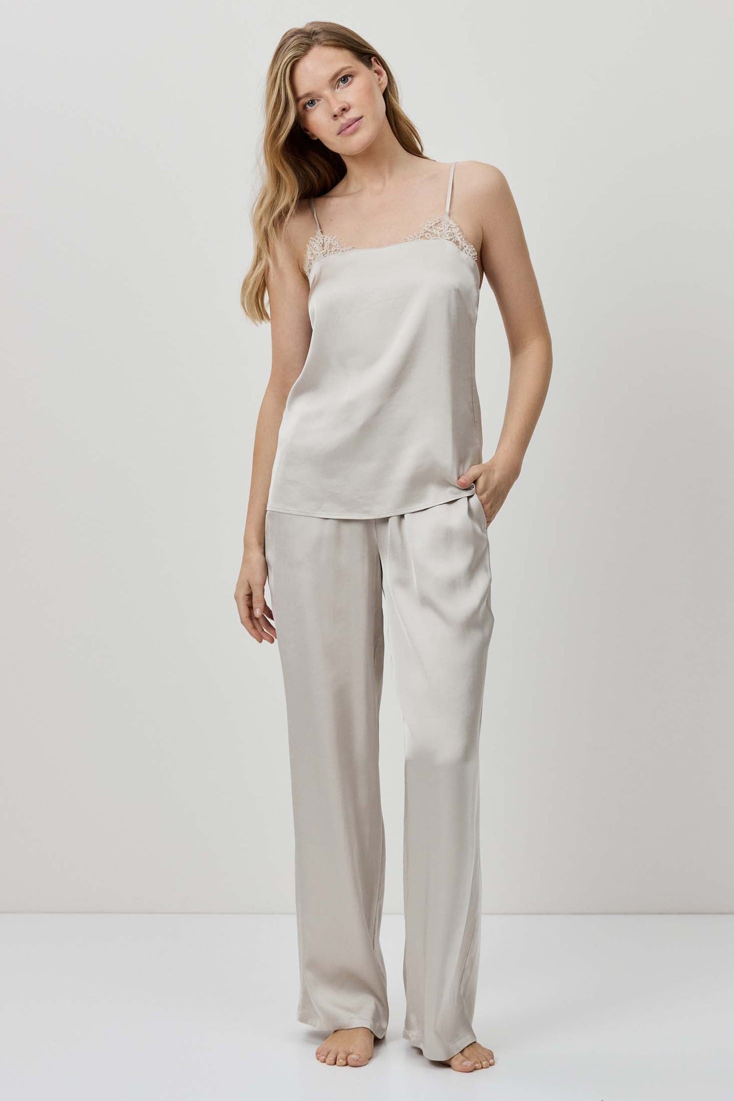 Woman wearing a beige slip dress and pants set on a white background