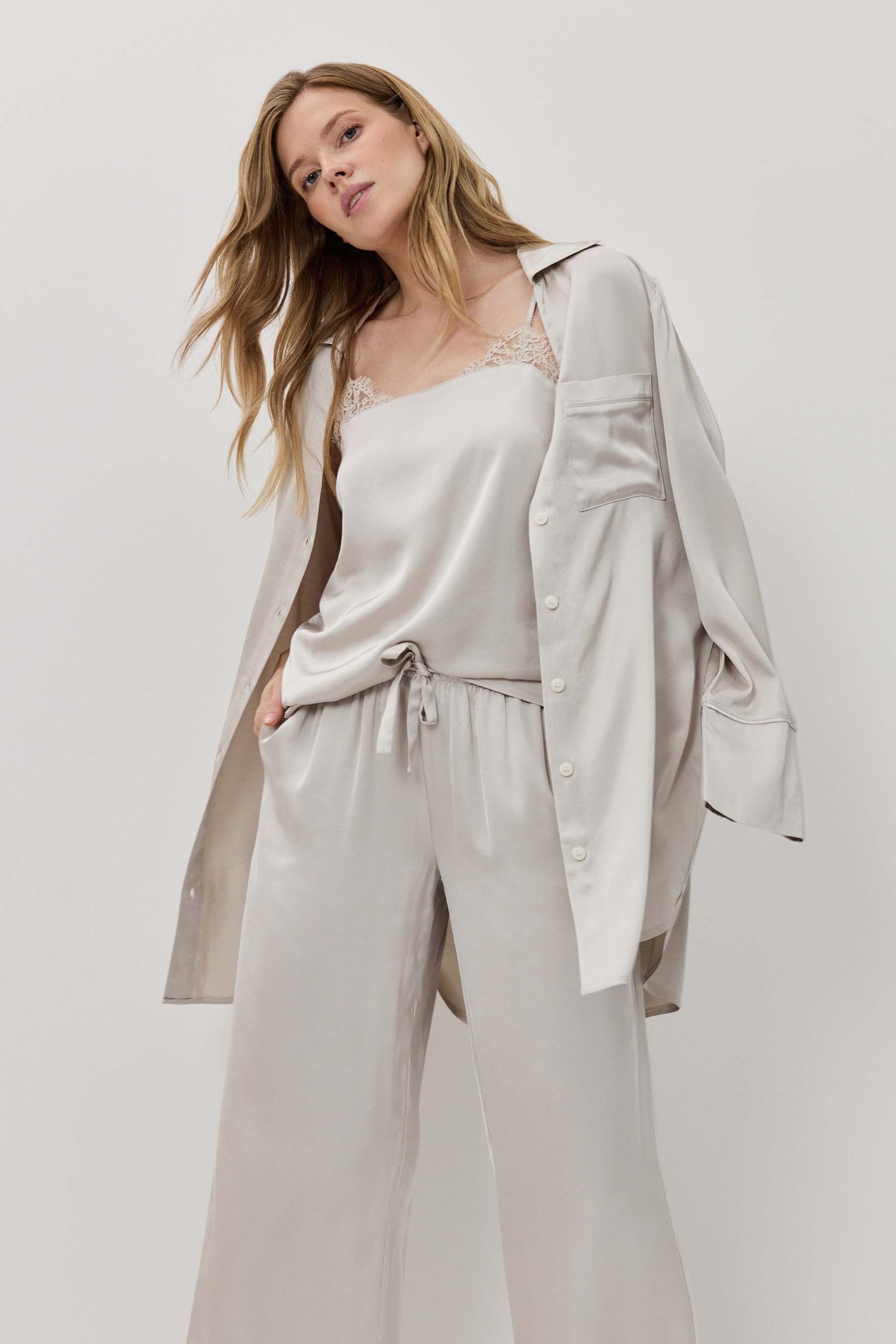 Woman wearing a light gray outfit with a matching jacket on a white background