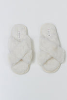 Pair of white fluffy slippers on a light gray background