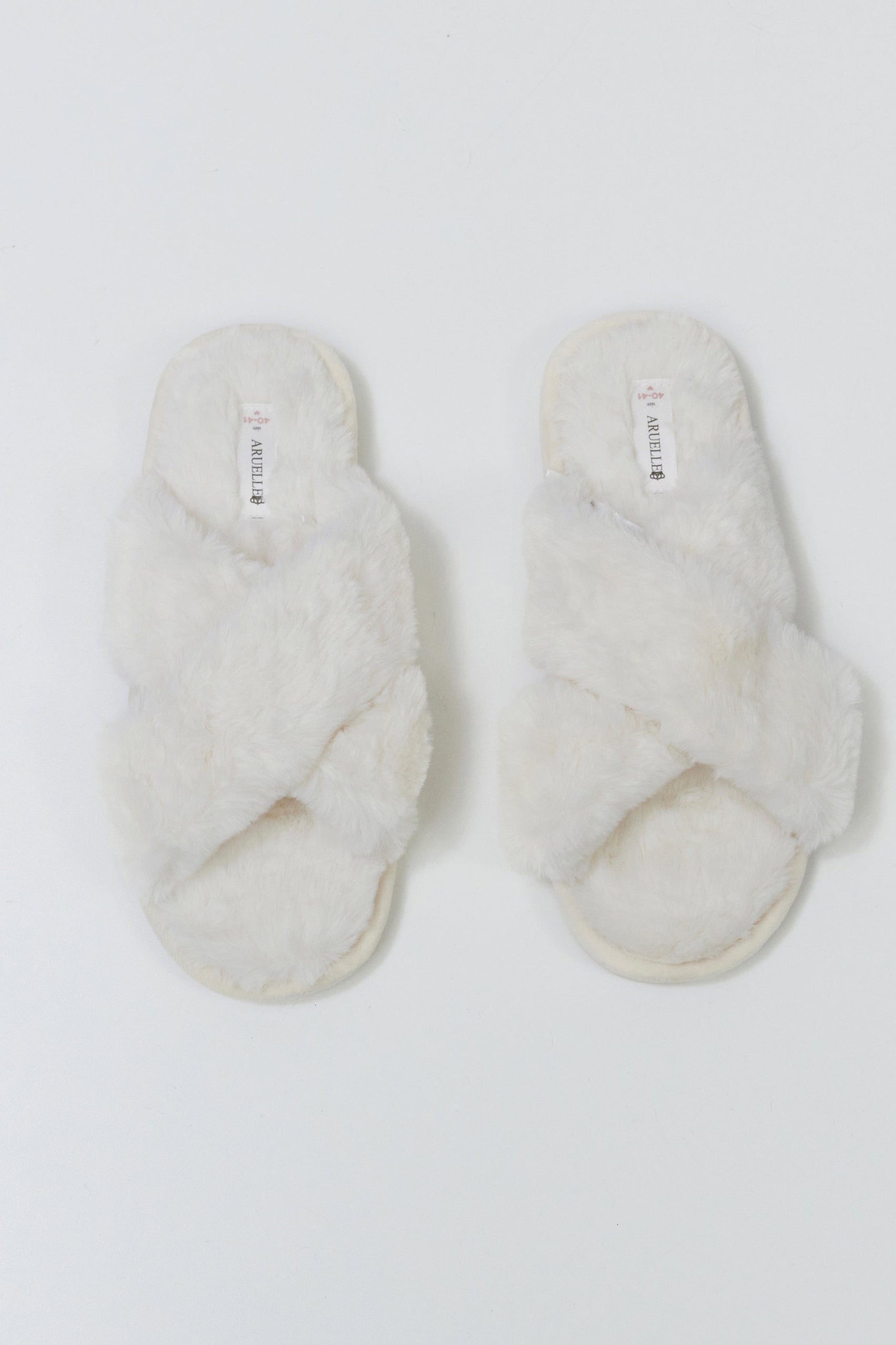 Pair of white fluffy slippers on a light gray background