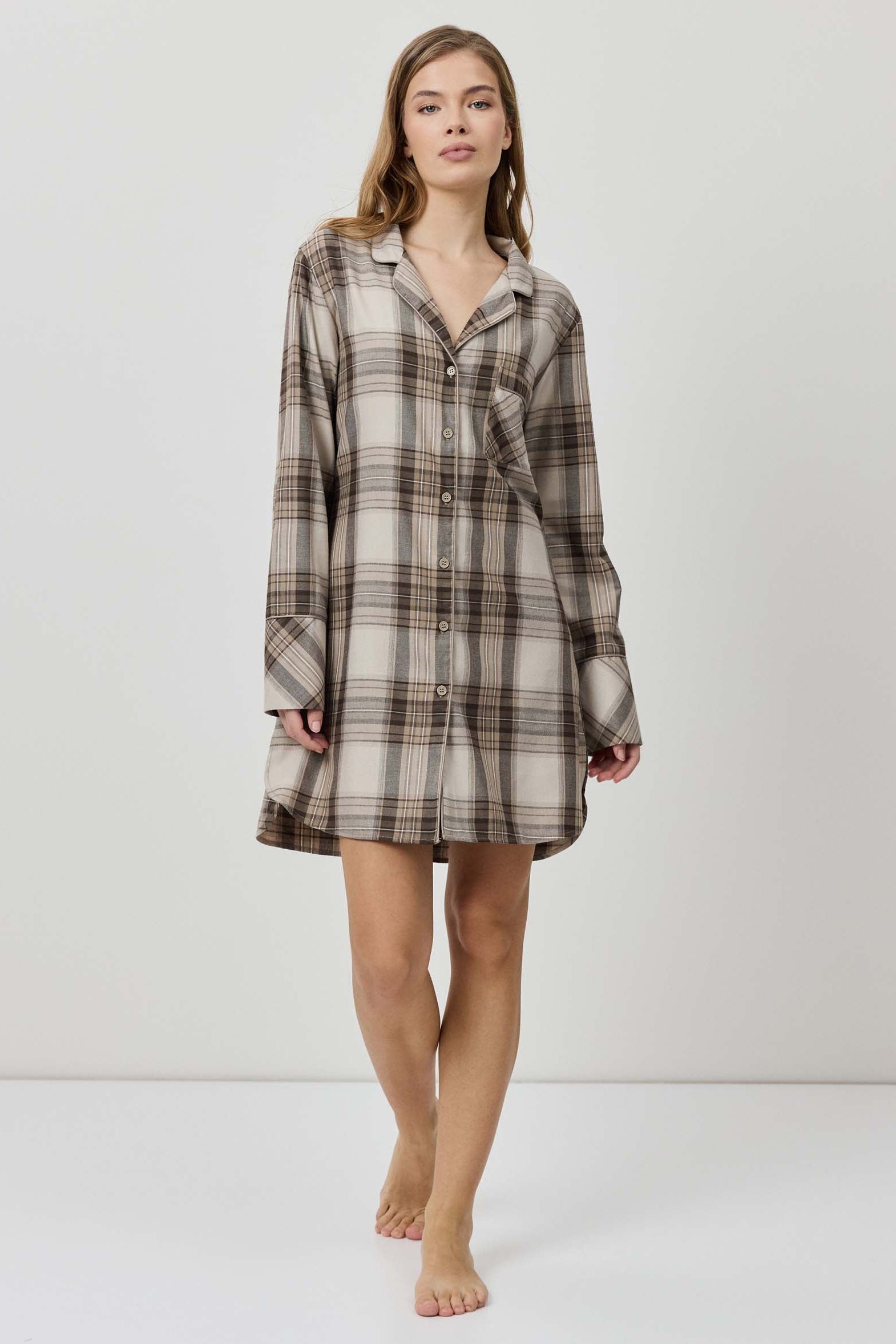 Woman wearing a plaid shirt dress against a white background