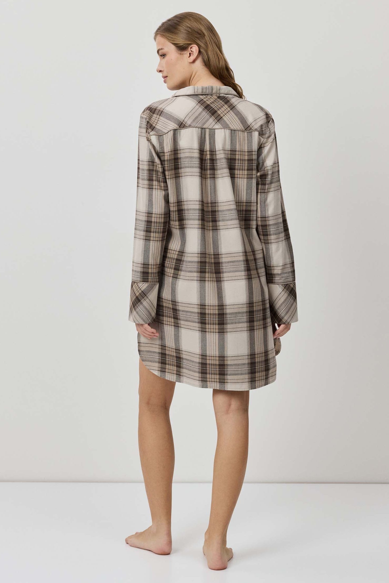 Woman wearing a plaid shirt dress against a white background