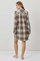 Woman wearing a plaid shirt dress against a white background