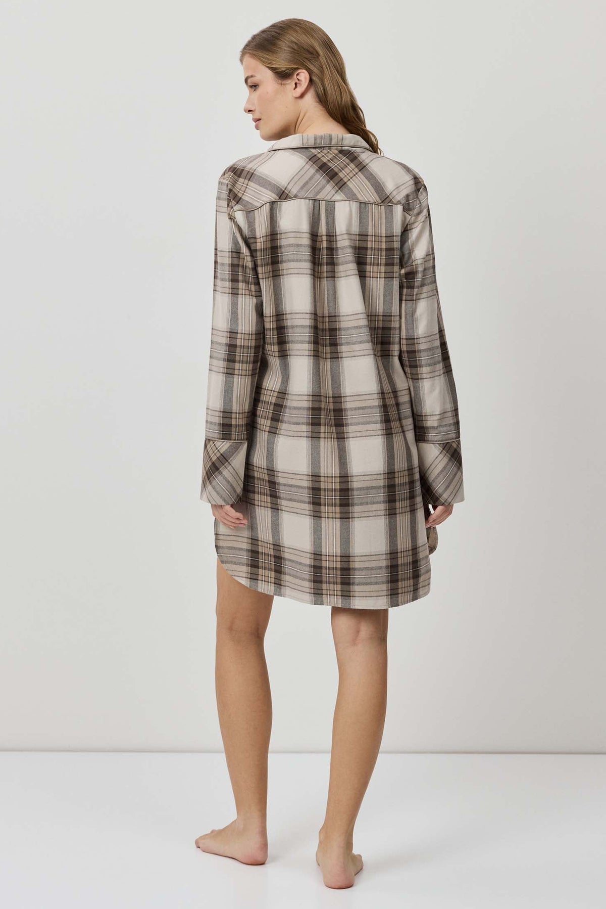 Woman wearing a plaid shirt dress against a white background