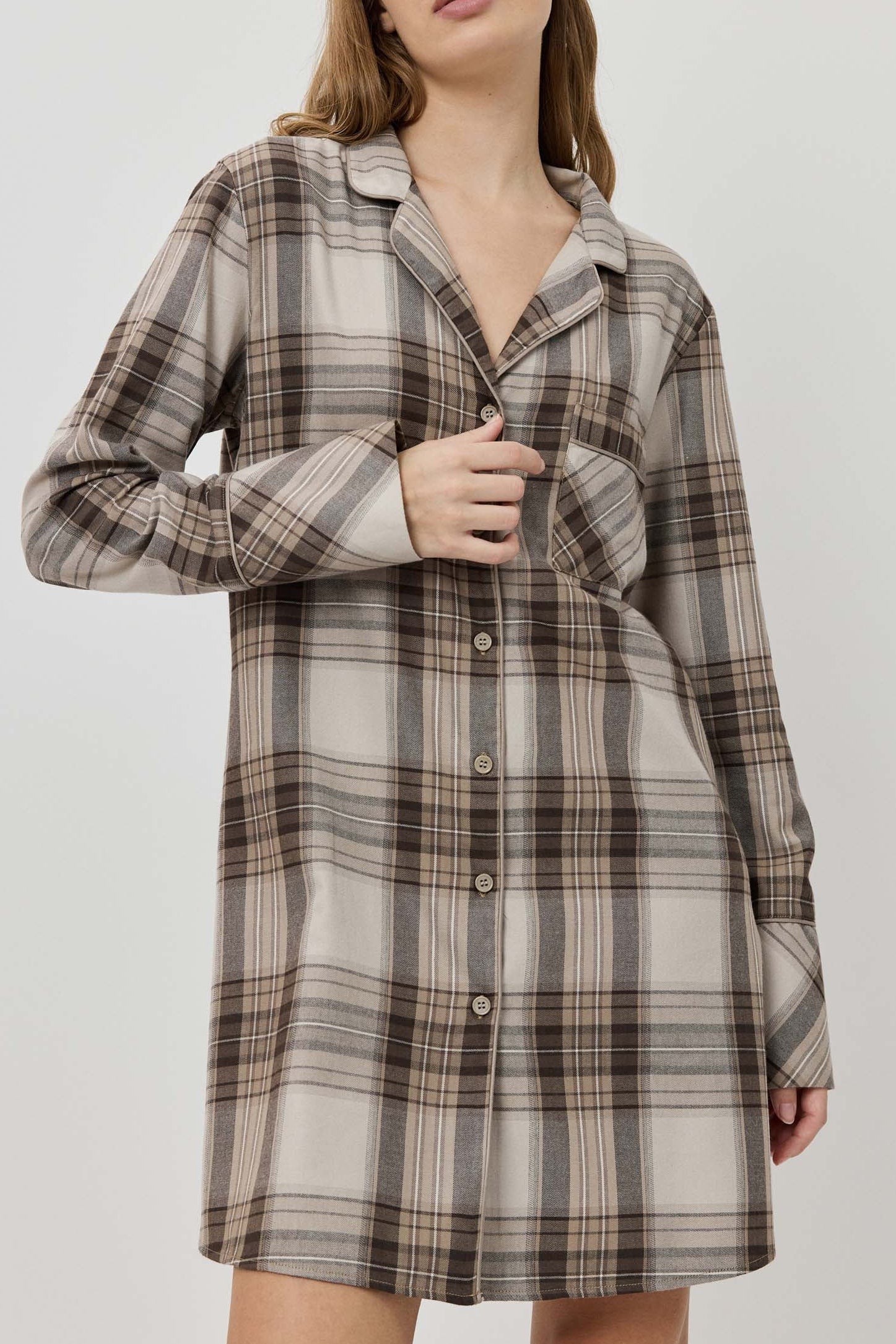Woman wearing a plaid dress against a plain background