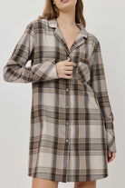 Woman wearing a plaid dress against a plain background