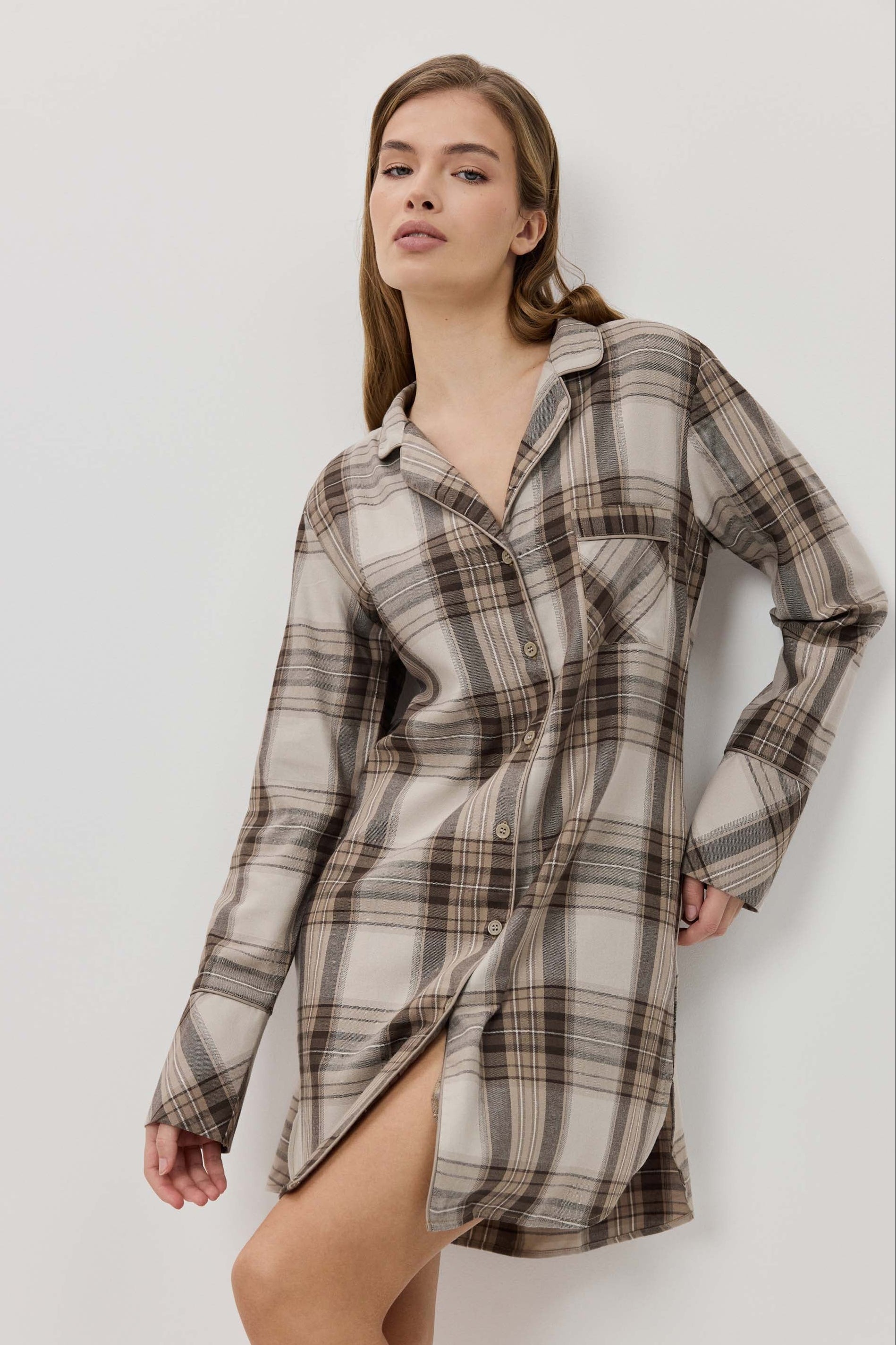Woman wearing a plaid shirt dress against a plain background