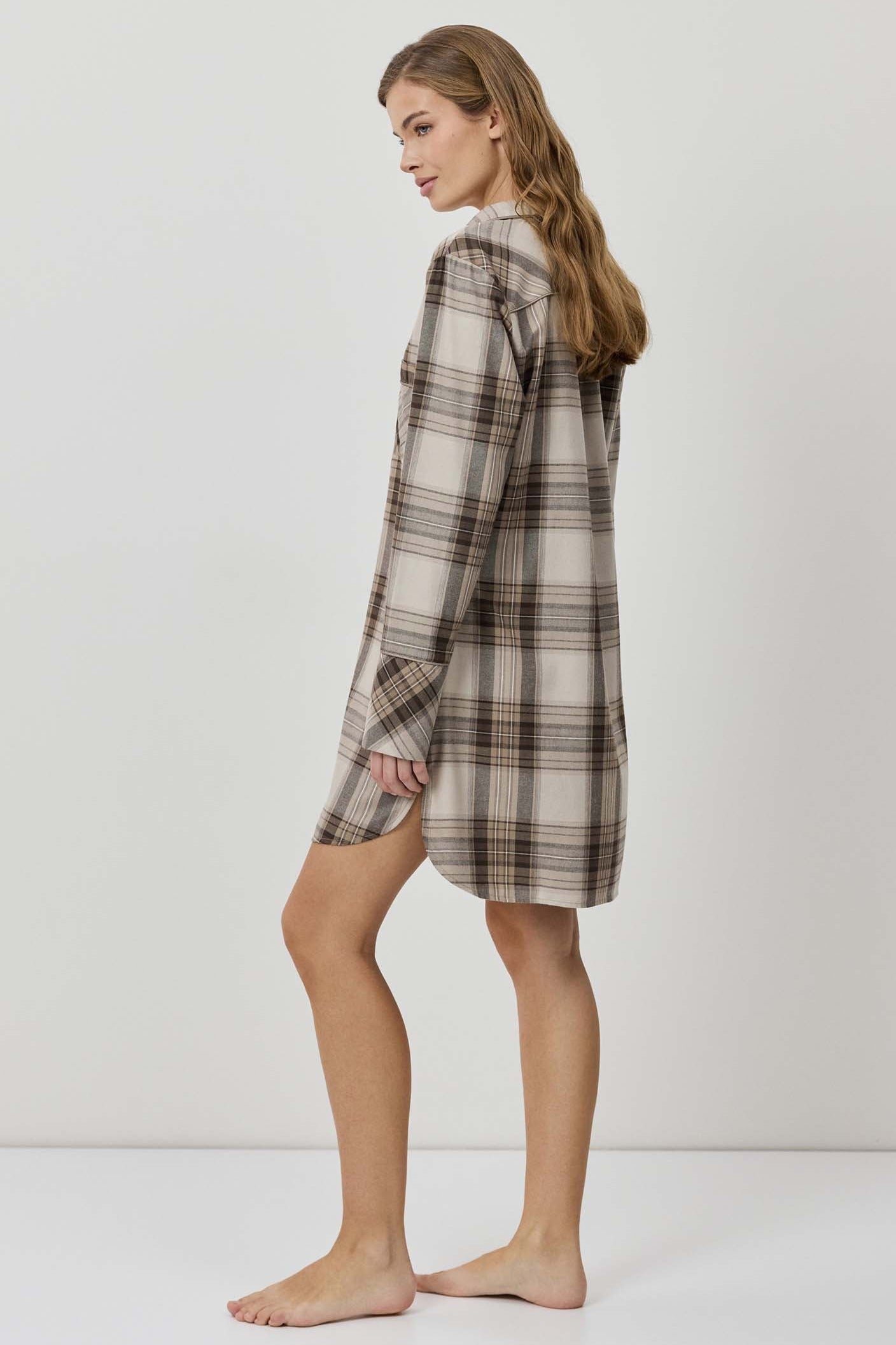 Woman wearing a plaid shirt dress against a white background