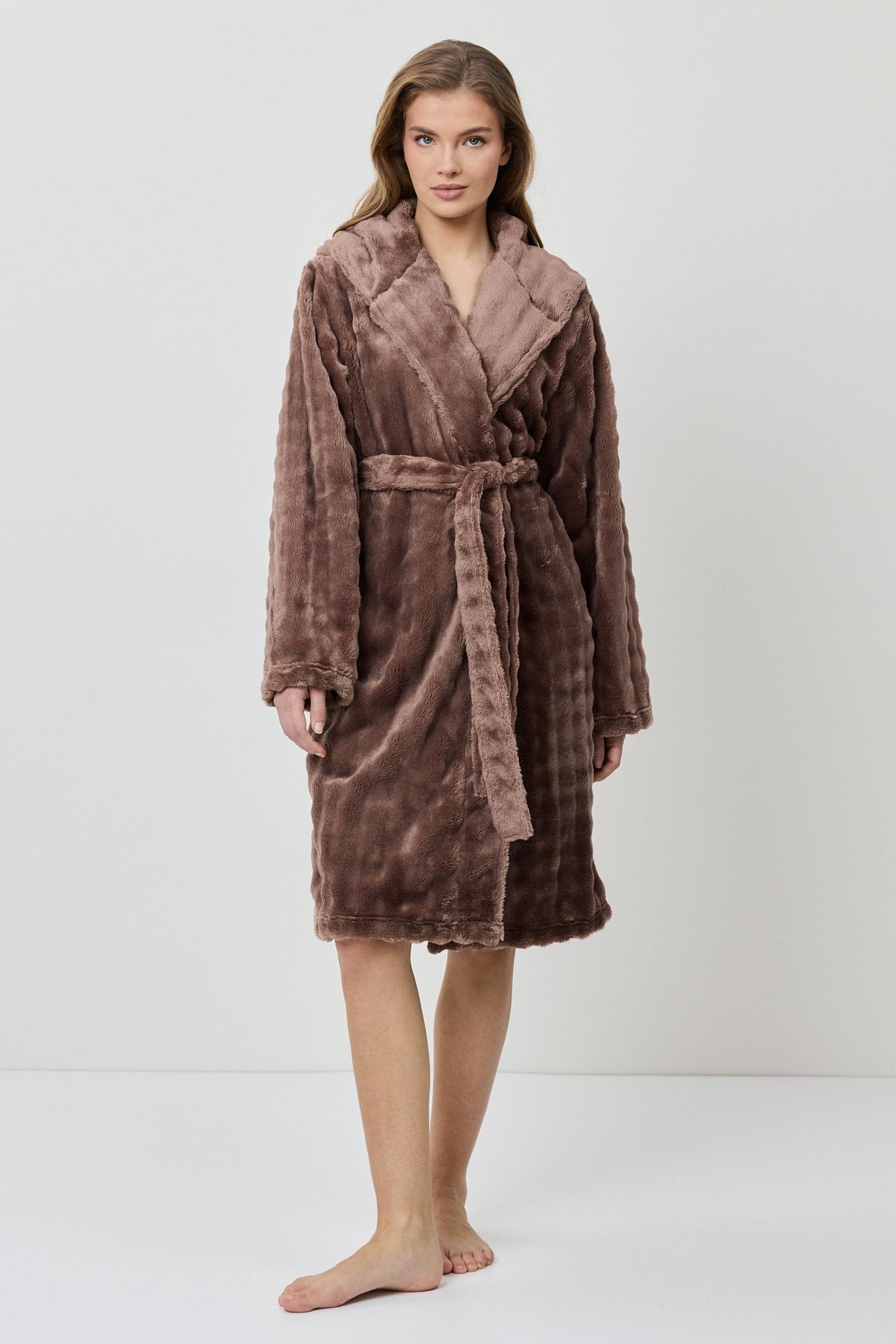 Woman wearing a brown plush robe on a white background