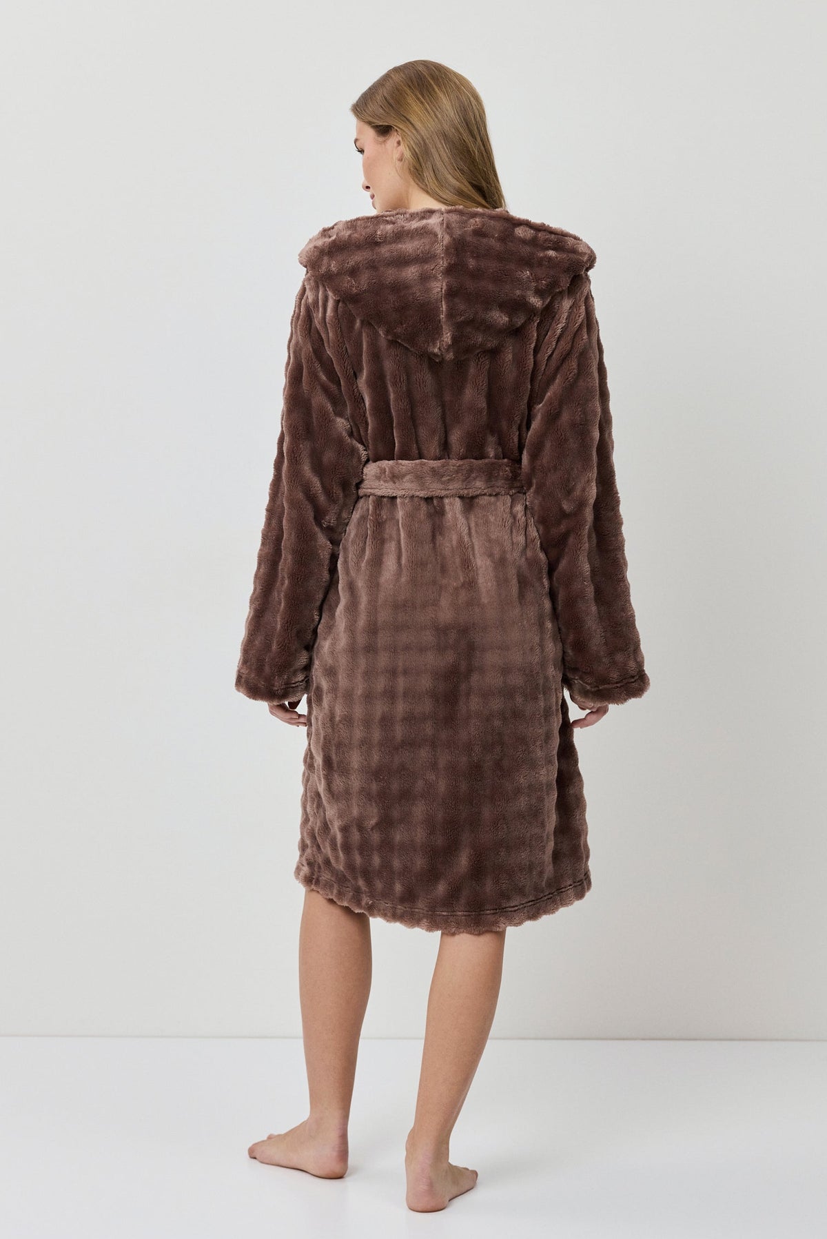 Woman wearing a brown plush robe against a white background